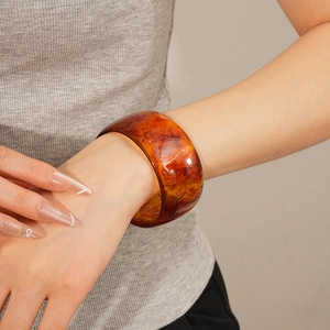 Detailed view of an amber resin bangle with marble texture on a woman's wrist