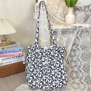 Macro shot of large butterfly print canvas tote bag on white lace with home decor items