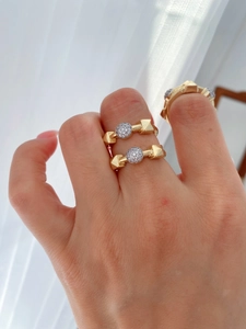 Close-up of stacked gold rings with geometric rockstuds and pavé set crystals on fingers