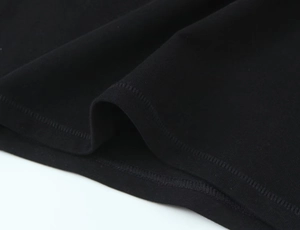 Détail des coutures à double aiguille et de la maille en coton sur un haut noir à manches