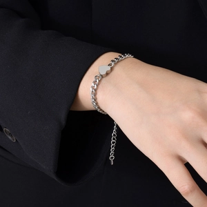 Close-up of silver stainless steel heart pendant bracelet on wrist with thick chain