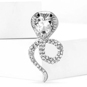 Detailed view of cobra brooch with sparkling rhinestones on a white geometric stand