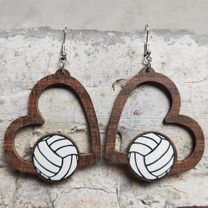Detail von herzförmigen Holzohrringen mit Volleyballmuster auf rustikalem Hintergrund
