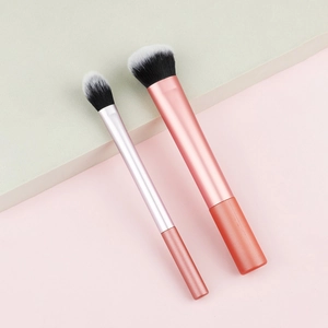 Close-up of pink makeup brushes with dual-tone synthetic bristles on a geometric background
