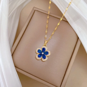 Detailed macro view of a gold five-leaf flower pendant with blue petals and crystals