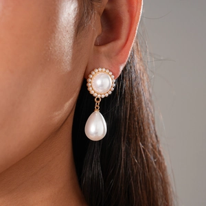 Close-up of elegant gold earrings with white imitation pearls and sunflower shaped studs