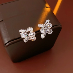 Makroaufnahme von Silber-Ohrsteckern mit glitzernden Zirkonia-Steinen auf Lederbox