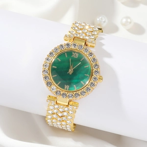 Close-up of emerald green dial watch with gold rhinestone strap on white silk backdrop