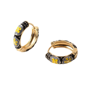 Vintage gold hoop earrings with black enamel and yellow floral patterns on white background