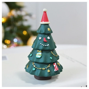 Close-up of green resin Christmas tree figurine with a cute face and red hat decor
