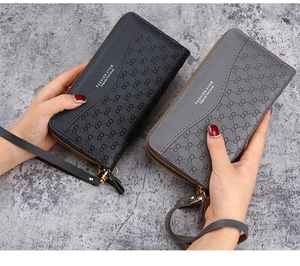 Detail of long zipped wallet with embossed texture and detachable wrist strap