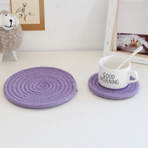 Detail of purple cotton woven coasters in large and small sizes on a minimalist dining table