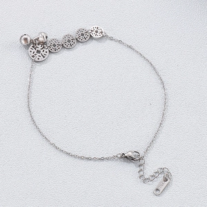 Macro detail of silver stainless steel anklet with vintage coins and tiny bells
