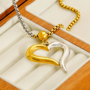 Detailed macro view of two-tone heart pendant on a box chain inside a jewelry box