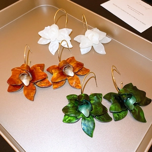 Retro resin flower earrings in white, amber, and dark green on a gold metal tray