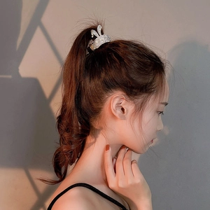 Détail d'une pince à cheveux couronne argentée avec perles sur une queue de cheval haute