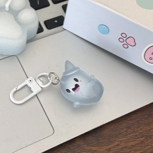 Macro shot of light blue luminous ghost keychain with metal clip on a desk setup