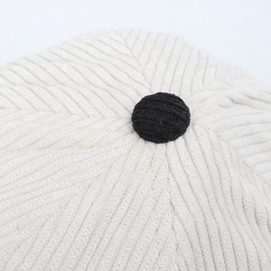 Macro shot of off-white corduroy fabric texture on baseball cap with black top button