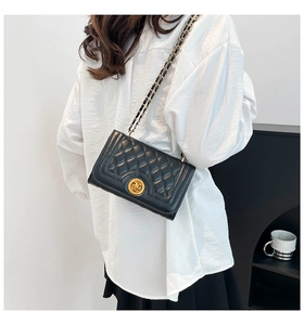 Quilted black leather shoulder bag with gold chain strap shown on a model's shoulder