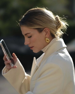 Close-up of a model wearing chunky gold textured hoop earrings in a modern street style