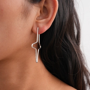 Close-up of minimalist silver geometric cross star earrings on female model