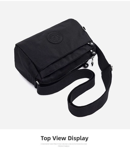 Detail view of the black nylon crossbody bag featuring multiple zipper compartments