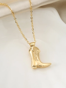 Detailed close-up of a golden cowboy boot pendant on a delicate cable chain necklace