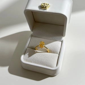 Macro shot of a pear-cut yellow gemstone ring presented in a white leather gift box