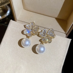 Detailed close-up of a floral pearl earring with sparkling crystals on gold metal base