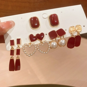 Close-up of five-pair retro burgundy earring set with resin pearls and gold accents