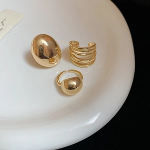 Detailed view of three polished gold adjustable rings on white porcelain for luxury styling