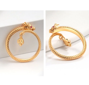 Detailed macro view of golden dragon open ring with red gem eyes and hanging leaf charm