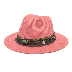 Detail of pink straw fedora featuring bohemian beads, turquoise stone, and tassel trim
