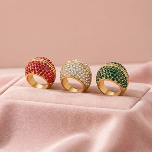 Three gold vintage rings with red white and green pavé crystals on pink velvet