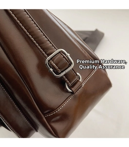 Close-up of dark brown wax leather bag showing silver buckle and white contrast stitching