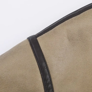 Detailed close-up of beige suede fabric and brown leather piping with precise stitching