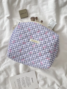 Quilted purple gingham makeup bag with pink bow patterns and zipper closure on white fabric