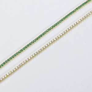 Detailed macro view of gold tennis chains with inlaid green and clear zircon stones