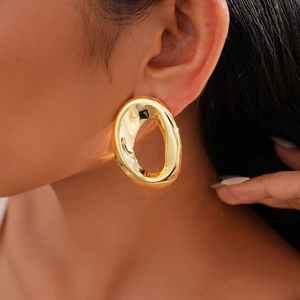 Macro shot of large irregular oval golden earrings with high-gloss mirror polished finish