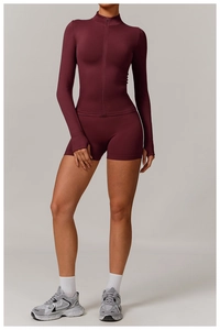 Detail of burgundy yoga set featuring zip-up jacket with thumbholes and high waist shorts