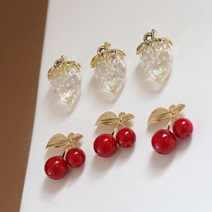 Detailed view of DIY strawberry and cherry pendants with gold edges for jewelry making