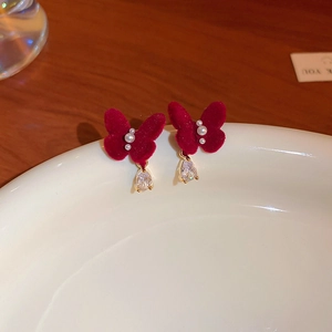 Detailed close-up of red velvet butterfly earrings with pearls and teardrop crystal