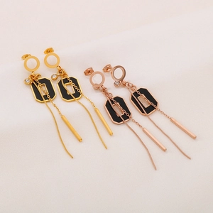 Détail de boucles d'oreilles à pompon long en or et or rose avec émail noir et petits strass