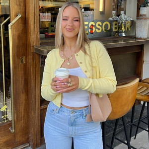 Détail d'un cardigan en maille jaune avec boutons dorés et accessoires en terrasse