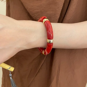 Close-up of red marble texture acrylic bracelet with gold metal accents on wrist
