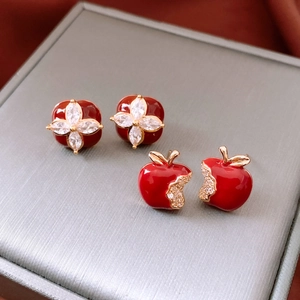Detail of red enamel clover and apple earrings with crystal accents on a jewelry box