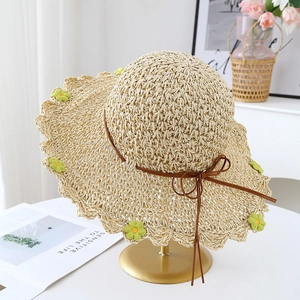 Handwoven beige sun hat with wide wavy brim and floral accents for summer beach wear