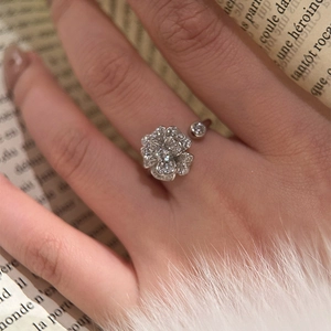 Detail of camellia flower open ring with pave-set zircons worn on hand over fur