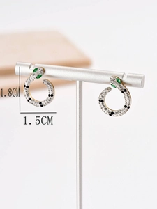 Detailed view of silver snake hoop earrings with zircon pavé and green crystal eyes
