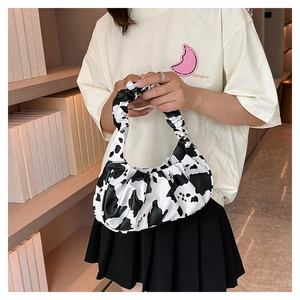 Detailed view of the cow print pattern and ruched handle on this crescent-shaped shoulder bag